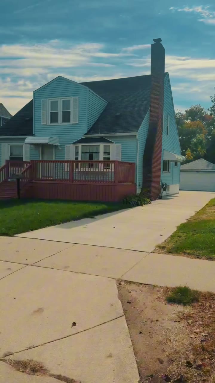 Still from Alan Lewandowski's campaign video: a sunlit Port Huron house with a red-brick chimney and a wooden front porch