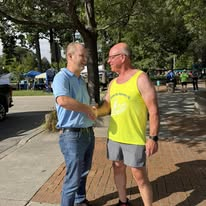 Alan Lewandowski shaking hands with a runner at a community event in Port Huron