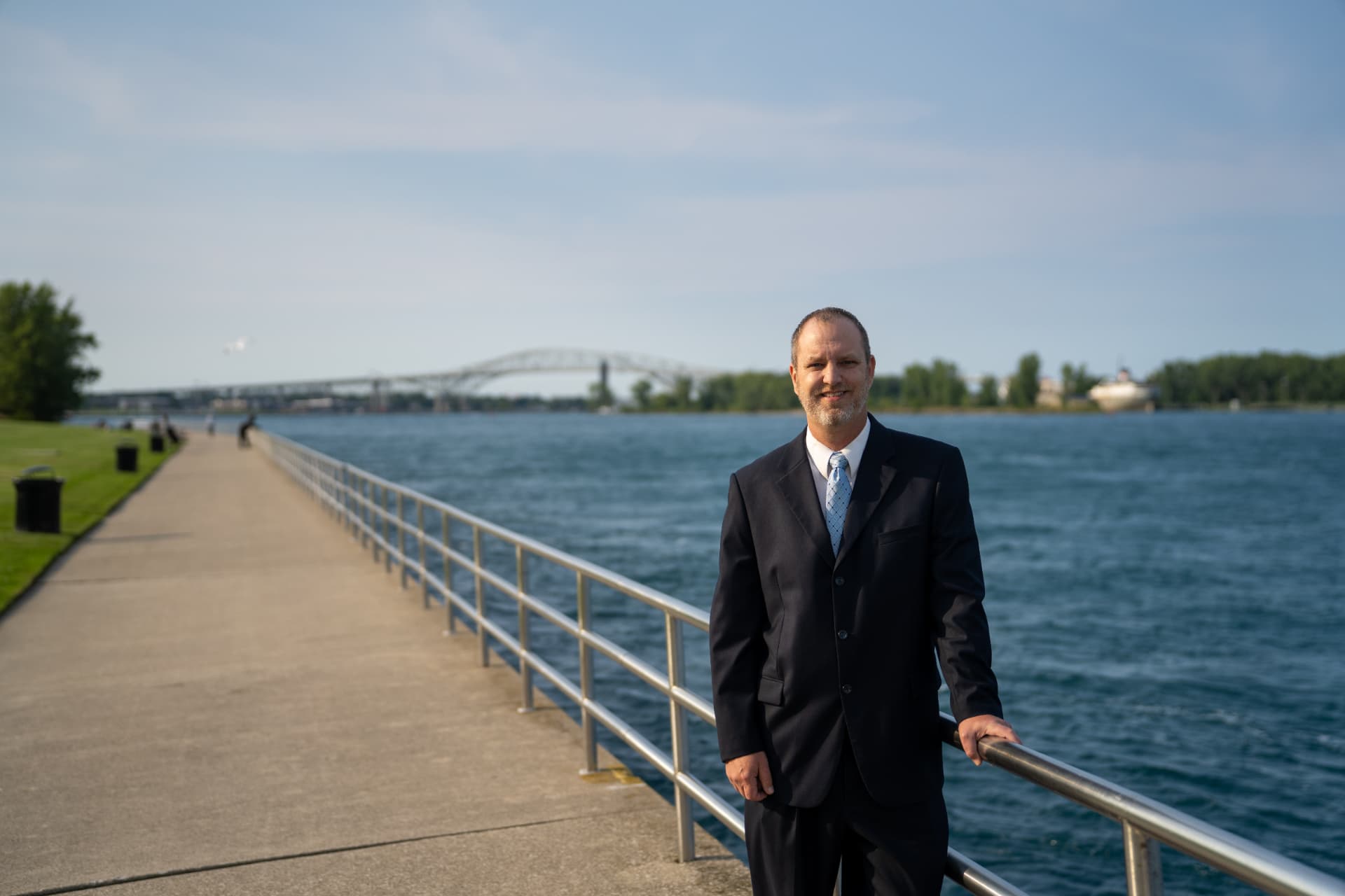 Alan Lewandowski on the Port Huron waterfront with the Blue Water Bridge in the background